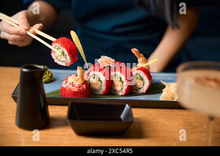 Frau nimmt ein Sushi aus dem Set mit Essstäbchen und genießt Geschmack Stockfoto