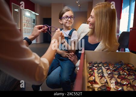 Der Berater hilft, eine Brille für ein kleines Mädchen zu wählen Stockfoto