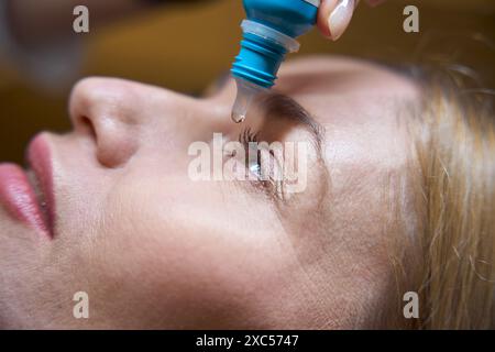 Die blonde Frau hat spezielle Tropfen in die Augen Stockfoto