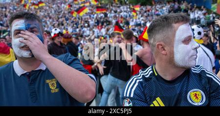 München, Deutschland. Juni 2024. Andrew Anderson (l) und Stephen Scott aus Klimqrnock, Schottland, sind in der offiziellen Fanzone im Olympischen Park, umgeben von jubelnden deutschen Fans, nicht sehr begeistert. Dies ist die UEFA-Fanzone während der Fußball-Europameisterschaft. Quelle: Stefan Puchner/dpa/Alamy Live News Stockfoto