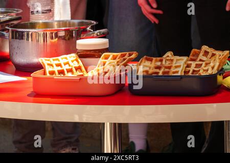 Ein Tisch für ein Picknick, mit Waffelbehältern, einem Stapel Pfannkuchen, einem Schokoriegel und anderen Picknickutensilien. Stockfoto