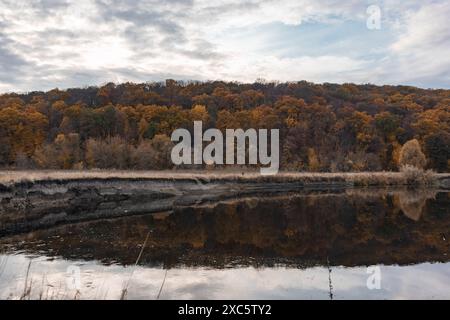 Herbstbiegung am Fluss mit Bäumen am Flussufer mit Reflektionen. Der herbstliche Fluss Siwerskyi Donets in der Ukraine Stockfoto