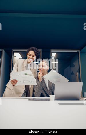 Zwei weibliche Kollegen diskutieren das Projekt, bevor sie der Teamleiterin im Büro eine Präsentation zeigen Stockfoto