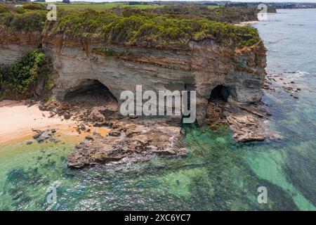 Aus der Vogelperspektive auf eine felsige Landzunge mit unterschnittenen Höhlen bei Inverloch in Gippsland, Victoria, Australien Stockfoto