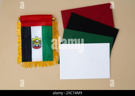 Kleine Flagge der VAE auf beigefarbenem Hintergrund mit bunten Umschlägen. Kopierbereich. Vorlage für Werbeanzeigen vortäuschen. Reisegutschein mit dem nationalen Symbol der Vereinigten Arabischen Emirate. Besuchen Sie Dubai Concept Stockfoto