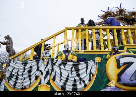 Zulu-Krewe-Mitglieder in ausgeklügelten Federkostümen und Gesichtsfarbe treffen sich vor einem Laden und bereiten sich auf die jährliche Mardi Gras-Parade in New Orleans vor. Stockfoto