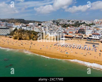 Küstenstadt mit Sandstrand, vielen Badegästen und Gebäuden entlang der Küste, aus der Vogelperspektive, Albufeira, Faro, Algarve, Portugal Stockfoto