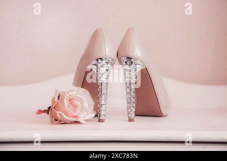 Elegante High Heels mit Kristalldetails neben einer zart platzierten rosa Rose Stockfoto