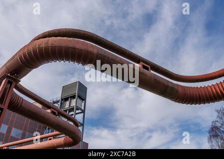 Industrieszene mit rostigen Rohren und einem Gebäude unter blauem Himmel, Essen, Ruhrgebiet, Deutschland Stockfoto