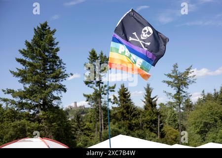 Adenau, Deutschland, 8. Juni 2024: Im Hintergrund ist die Nürnburg zu sehen, während eine Regenbogenfahne und eine Piratenfahne auf einem Zelt an einem der Felsen am Himmel fliegen Stockfoto