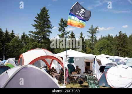 Adenau, Deutschland, 8. Juni 2024: Im Hintergrund ist die Nürnburg zu sehen, während eine Regenbogenfahne und eine Piratenfahne auf einem Zelt an einem der Felsen am Himmel fliegen Stockfoto