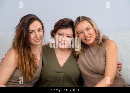 Porträt einer älteren Mutter mit erwachsenen Töchtern auf dem Sofa Stockfoto