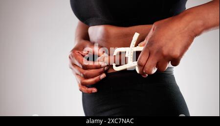 Afrikanische Frau mit einem Fettschieber zur Messung von Bauchfett, mit Schwerpunkt auf bariatrischer Gewichtsabnahme und Fettleibigkeit in der schwarzen Gemeinschaft. Stockfoto