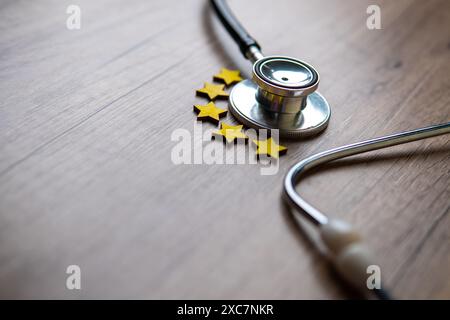 Nahaufnahme des Stethoskops und fünf Sterne auf Holztisch mit Kopierraum. Patientenerfahrung, Zufriedenheit, Review und Bewertungskonzept. Stockfoto