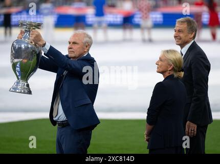 München, Deutschland. Juni 2024. Fußball: UEFA Euro 2024, Europameisterschaft, Deutschland - Schottland, Vorrunde, Gruppe A, Heidi Beckenbauer (M), Witwe des ehemaligen Nationalspielers und Trainers Franz Beckenbauer, bringt die Trophäe mit Bernard Dietz (l) und Jürgen Klinsmann, den deutschen Kapitänen bei den Europameistertiteln 1980 und 1996, in die Arena. Quelle: Sven Hoppe/dpa/Alamy Live News Stockfoto