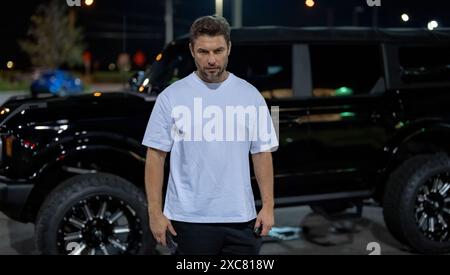 Ernster Mann in der Nähe des Autos Außenporträt. Ernster Hipster auf nächtlichem Straßenhintergrund. Seriöser Mann, Hipster sehen brutal aus. Wütender reifer Mann. Konflikt Stockfoto