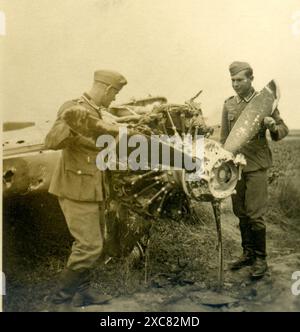 Zwei deutsche Soldaten untersuchen ein zerstörtes Flugzeug, IIWW Stockfoto