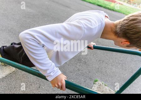 Junger Mann, der im Outdoor Gym Tauchübungen an parallelen Bars durchführt Stockfoto
