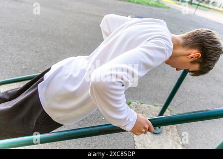 Junger Mann, der Dips auf parallelen Balken im Außenbereich durchführt Stockfoto