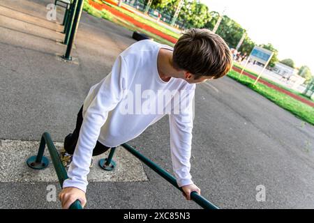 Junger Mann, der im Outdoor Gym Tauchgänge an parallelen Bars macht Stockfoto