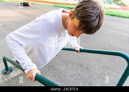 Junger Mann, der im Outdoor Gym Tauchgänge an parallelen Bars macht Stockfoto