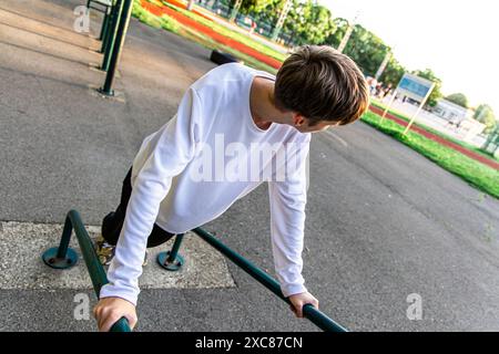 Junger Mann, der im Outdoor Gym Tauchgänge an parallelen Bars macht Stockfoto