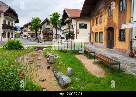 Die Marktgemeinde Mittenwald mit historischen Gebäuden Mittenwald liegt im Landkreis Garmisch-Partenkirchen, ist Deutschlands höchstgelegener Luftkurort und berühmt wegen der traditionellen Kunst des Geigenbaus. In der historischen Altstadt sind viele Häuser auf der Fassade mit kunstvoller Lüftlmalerei geschmückt. Direkt neben der historischen Altstadt liegt der Ortsteil Gries mit seinen historischen Gebäuden und den mit Blumen- und Pflanzenschmuck aufwendig gestaltete Freiflächen. Mittenwald Bayern Deutschland *** die Marktstadt Mittenwald mit historischen Gebäuden Mittenwald befindet sich in Stockfoto