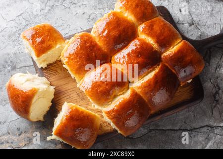 Süße hawaiianische Brotbrötchen für Sandwiches oder einfach nur zum Snack aus eigener Nähe auf dem Holzbrett auf dem Tisch. Horizontale Draufsicht von oben Stockfoto