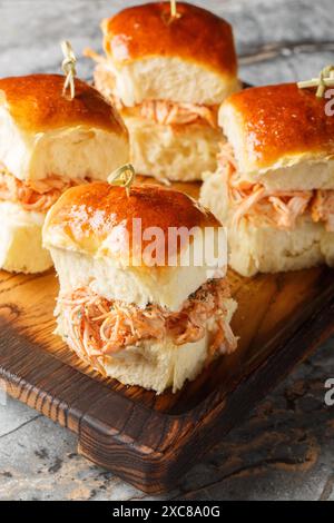 Hausgemachte hawaiianische Brötchen mit gezogenem Huhn und Käse aus nächster Nähe auf einem Holzbrett auf dem Tisch. Vertikal Stockfoto