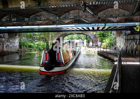 London, Großbritannien. Ein Binnenschiff, das unter einer Brücke in der Nähe des Camden Lock am Regents Canal vorbeifährt. Stockfoto