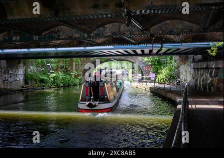 London, Großbritannien. Ein Binnenschiff, das unter einer Brücke in der Nähe des Camden Lock am Regents Canal vorbeifährt. Stockfoto