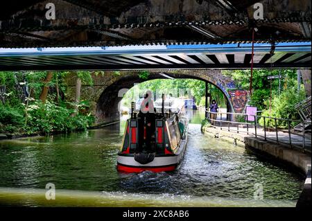 London, Großbritannien. Ein Binnenschiff, das unter einer Brücke in der Nähe des Camden Lock am Regents Canal vorbeifährt. Stockfoto