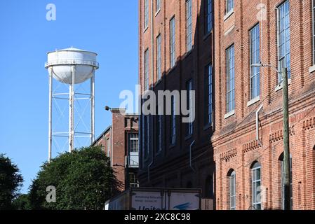 Ein Wasserturm erhebt sich über alten Tabaklagern, die in Wohnraum umgewandelt wurden, im historischen Viertel von Durham, North Carolina. Stockfoto