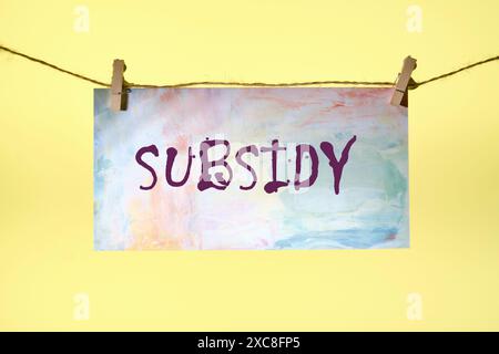 Geschäftskonzept. SUBVENTIONSWORT auf Papier, aufgehängt an einem Seil auf gelbem Hintergrund Stockfoto