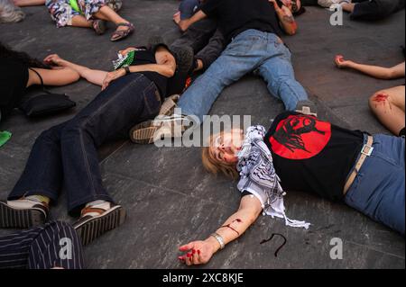 Madrid, Spanien. Juni 2024. Menschen, die auf der Straße liegen, als wären sie tot, bedeckt mit gefälschtem Blut während einer Darstellung der Folgen eines Bombenanschlags. Aktivisten protestieren gegen die Angriffe Israels im Gazastreifen und fordern einen dauerhaften Waffenstillstand in Palästina. Quelle: Marcos del Mazo/Alamy Live News Stockfoto