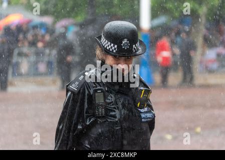 The Mall, Westminster, London, Großbritannien. Juni 2024. Die königliche Familie, massenhafte Bands und Truppen sind von der Horse Guards Parade zur Truppe der Farbe zurückgekehrt, auch bekannt als die Geburtstagsparade des Königs. Weiblicher Spezialkonstabler nass von starkem Regen Stockfoto