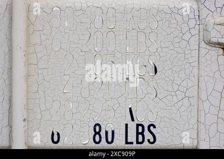 Auf einigen alten Behältern der Kite Surf Association Katwijk aan Zee entdeckte ich diese alten und verwitterten Zahlen und Buchstaben auf alten, rissigen weißen Pai Stockfoto