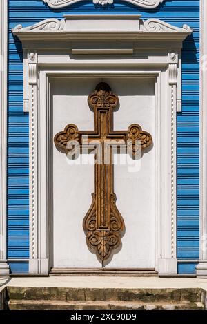 Großes Hölzernes Geschnitztes Kreuz, Das An Der Weißen Tür Der Blauen Kirche Hängt Stockfoto