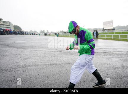 Ein als Jockey verkleideter Rennfahrer wird in einem Regenregen auf der Sandown Park Racecourse, Esher, gefangen. Bilddatum: Samstag, 15. Juni 2024. Stockfoto