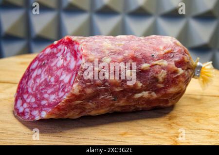 Salami auf einer Holzoberfläche, fokussiert auf Textur und Farbe, ideal für Lebensmittelblogs oder Artikel. Stockfoto