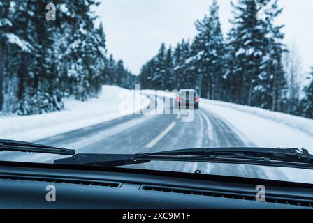 Ein Blick aus dem Inneren eines Autos, das auf einer verschneiten Straße in Schweden fährt. Die Scheibenwischer sind aktiv und entfernen den Schnee von der Windschutzscheibe. Die Straße ist windi Stockfoto