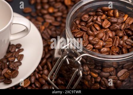 Ein Glasgefäß mit Kaffeebohnen und einer weißen Espresso-Tasse. Stockfoto