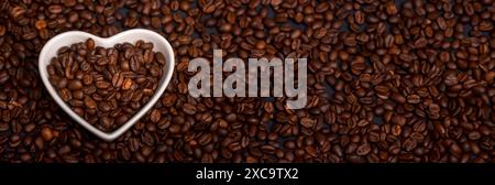 Herzförmiges Gericht mit Kaffeebohnen und Textur Hintergrund aus Bohnen. Ich liebe das Kaffeekonzept. Stockfoto