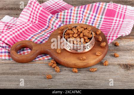 Mit Sesam beschichtete Erdnüsse mit Honig und Melasse, traditionelle türkische Nüsse. Eine kupferne Schüssel mit knusprigen asiatischen Sesam-Erdnüssen mit Sojasauce auf einem hölzernen Grafen Stockfoto