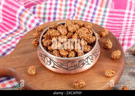 Mit Sesam beschichtete Erdnüsse mit Honig und Melasse, traditionelle türkische Nüsse. Eine kupferne Schüssel mit knusprigen asiatischen Sesam-Erdnüssen mit Sojasauce auf einem hölzernen Grafen Stockfoto