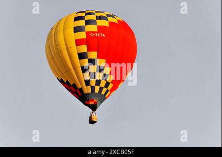 Heißluftballons, Tavarnelle, Toskana, Italien, Europa, ein orange-gelber Heißluftballon mit kariertem Muster fliegt hoch am klaren Himmel Stockfoto