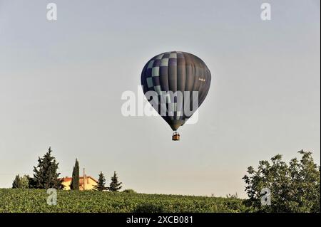 Heißluftballons, Tavarnelle, Toskana, Italien, Europa, ein blauer Heißluftballon fliegt über ein Feld mit einem Landhaus und Bäumen im Hintergrund Stockfoto