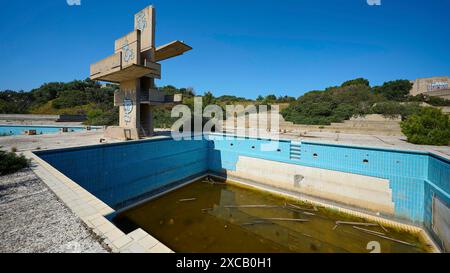 Altes verlassenes Schwimmbad mit Graffiti und algenbefallenem Wasser, umgeben von der Natur an einem sonnigen Tag, verlorener Platz, verfaultes Schwimmbad, Afandou Stockfoto