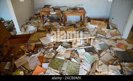 Verlassenes Zimmer mit verstreuten Büchern und Papieren, zerrissenen Möbeln und allgemeinem Chaos, verlorener Platz, verfaultes Schwimmbad, Afandou, Rhodos, Dodekanesisch Stockfoto