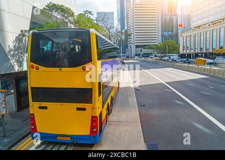 Doppeldecker-City-Shuttle-Bus an einer Haltestelle, um Passagiere abzusetzen und abzuholen, fährt die Straße hinunter, aus der Vogelperspektive. Stockfoto